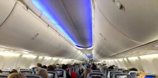 Airplane cabin with passengers seated and seatback screens