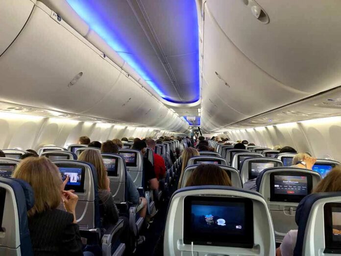 shutterstock_1373718830 Airplane cabin with passengers seated and seatback screens
