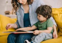 Parenting Has Never Looked More Different Woman reading a picture book with a young child on a yellow couch