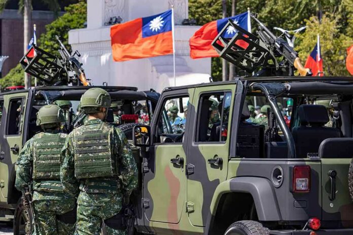 Soldiers beside camouflaged military vehicles with mounted guns and flags