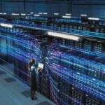 Technician with laptop in a large data center aisle