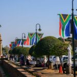 South African flags line a walkway near a bronze equestrian statue