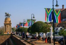 South African flags line a walkway near a bronze equestrian statue
