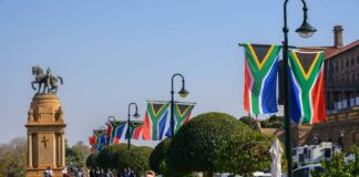 South African flags line a walkway near a bronze equestrian statue