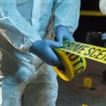 forensic investigators unrolling yellow barrier tape at night