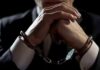 Businessperson in handcuffs with hands clasped