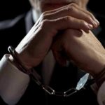 Businessperson in handcuffs with hands clasped