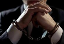 Businessperson in handcuffs with hands clasped