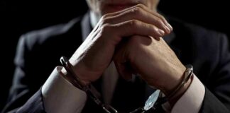 Businessperson in handcuffs with hands clasped