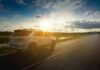 White SUV parked on a rural road at sunset