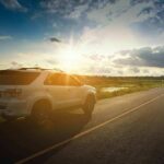 White SUV parked on a rural road at sunset