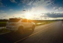 White SUV parked on a rural road at sunset