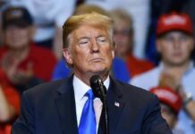 No Iran Help? Trump Rethinks The War Games man in suit speaking at a rally podium