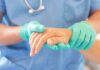 Healthcare worker in gloves holding a patient's hand