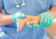 Healthcare worker in gloves holding a patient's hand