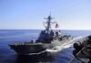 naval destroyer sailing at sea with flag flying