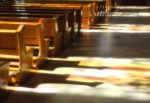 Wooden church pews with stained glass light on the aisle