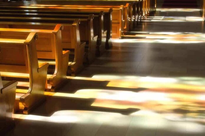 Wooden church pews with stained glass light on the aisle