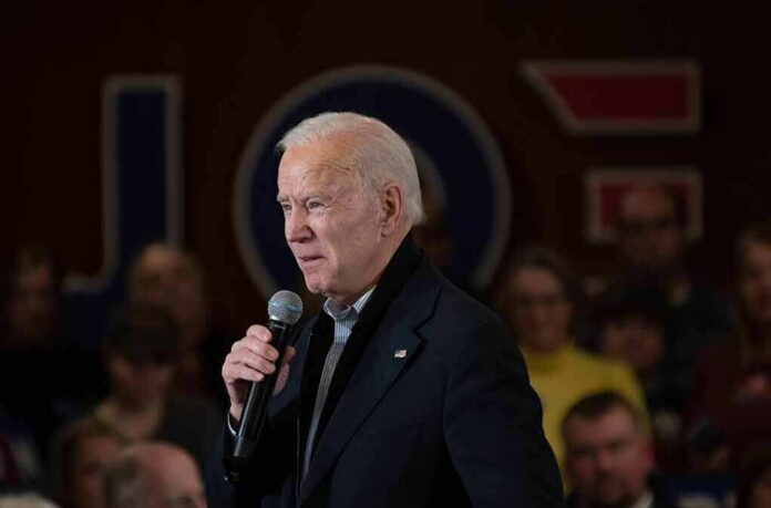 older man speaking into a microphone at an indoor event