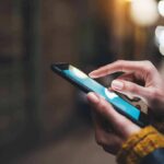 Hands using a smartphone outdoors at night