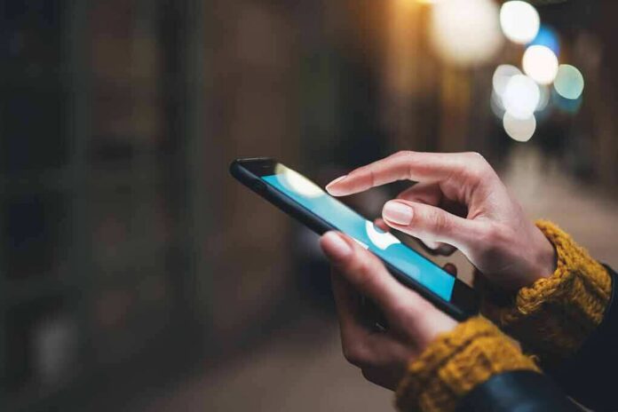 Hands using a smartphone outdoors at night