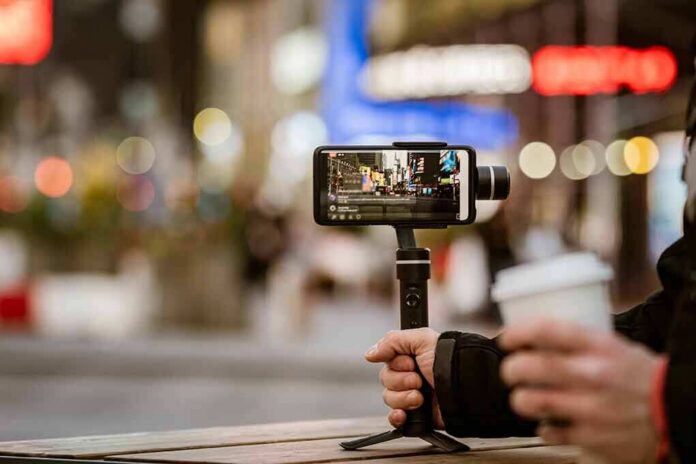 shutterstock_1682035603 Smartphone on a handheld gimbal filming a city street at night