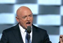 Bald man in suit speaking into a microphone
