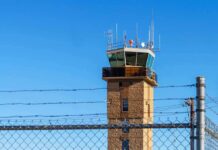 Airport control tower behind chain-link and barbed-wire fence