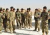 Soldiers in camouflage gather for a briefing outdoors