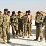 Soldiers in camouflage gather for a briefing outdoors