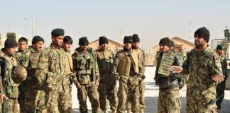 Soldiers in camouflage gather for a briefing outdoors