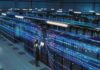 Technician with laptop in a large data center aisle