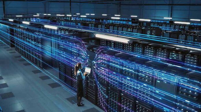 Technician with laptop in a large data center aisle
