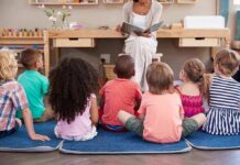 children sitting on mats listening to a teacher read a book
