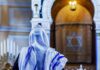 Person in white and blue prayer shawl facing ornate interior