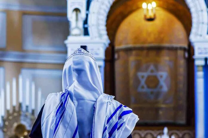 Person in white and blue prayer shawl facing ornate interior