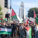 Protesters holding Palestinian flags gather in a city street