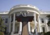 Press podium with presidential seal in front of the White House