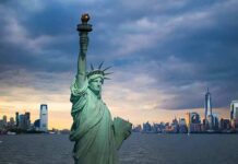 Statue of Liberty with city skyline at dusk