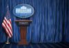 The Battle Over Press Access Isn’t Over White House press briefing podium with U.S. flag and blue curtain