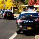 A Missing GPS Monitor Sparked A Two-Day Manhunt Police cars with lights on near school buses on a city street