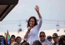 Kamala Harris speaking at outdoor rally, Paul Scholes in the crowd