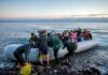 People arriving in a crowded inflatable boat at a rocky shore