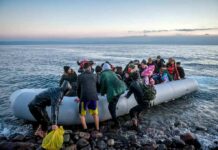 People arriving in a crowded inflatable boat at a rocky shore