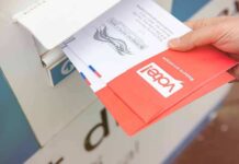 Hand dropping mail-in ballots into a drop box