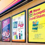 Store window posters advertising SNAP EBT acceptance and product deals