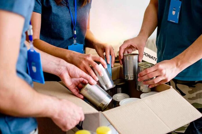 Hands sorting canned food into a donation box