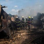 Explosive Threat Forces Emergency Factory Evacuation Firefighters amid twisted metal and smoke at a disaster site