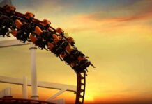 roller coaster train rounding a curve at sunset