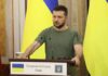 Man at a podium with Ukrainian flags
